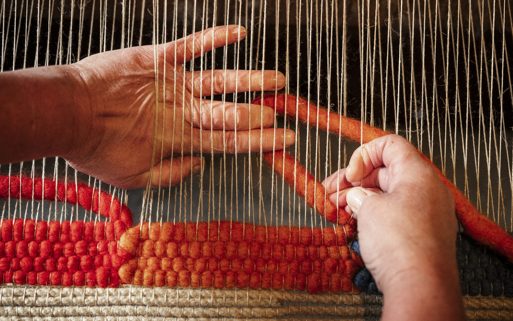 Nahaufnahme von Händen beim Teppichweben mit Wolle. Foto: Habbishaw Teppiche